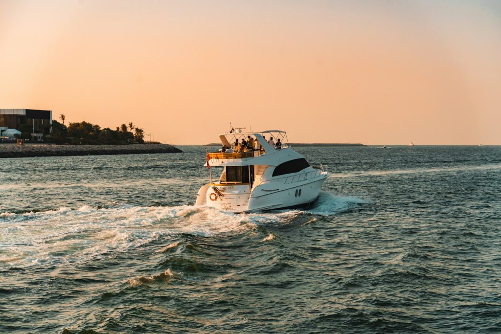 A white yacht cruises on the ocean at sunset.